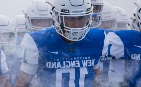 UNE football team members walk through the fog